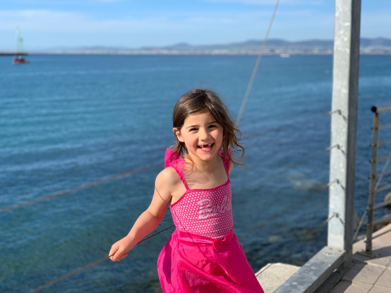 Mica in a pink Barbie dress by the sea