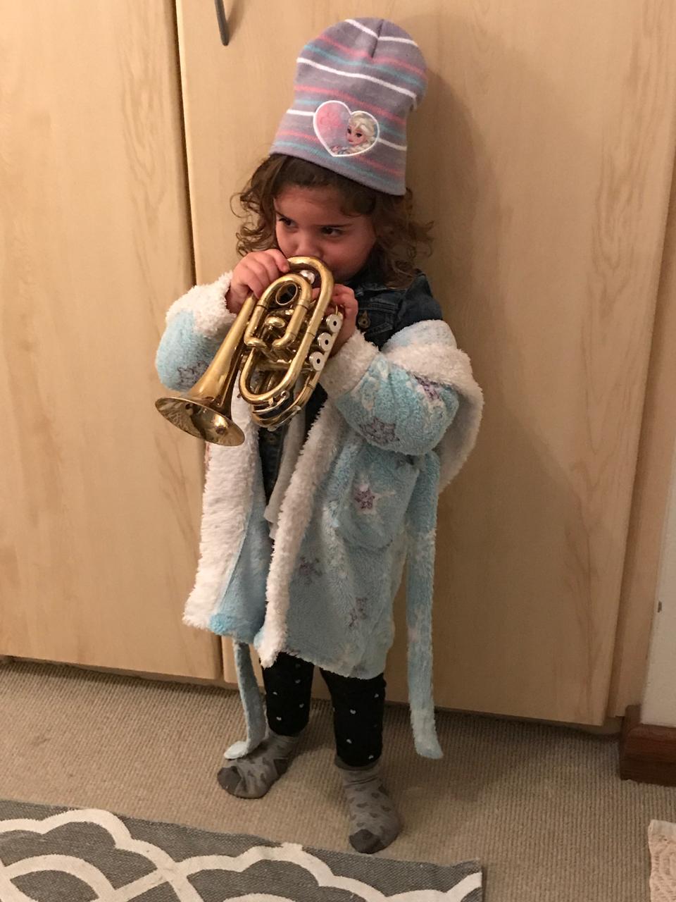 Mica playing the trumpet in a cosy outfit
