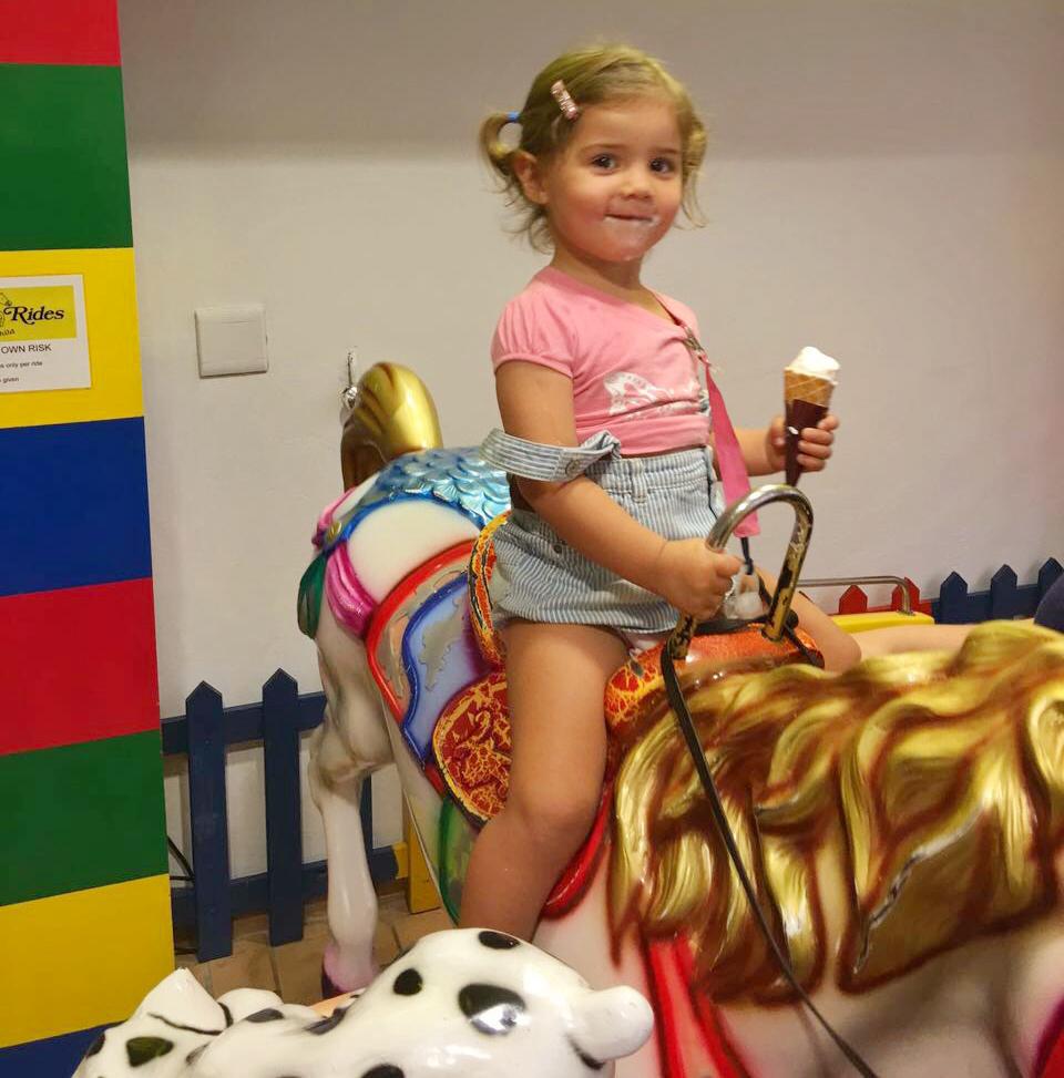 Mica on a carousel horse with ice cream